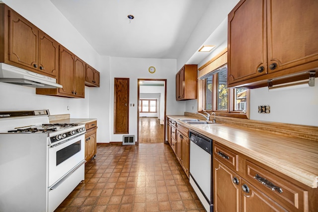 kitchen with white gas stove, under cabinet range hood, a sink, light countertops, and dishwasher