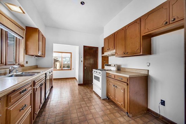 kitchen featuring white range with gas stovetop, brown cabinets, light countertops, under cabinet range hood, and a sink