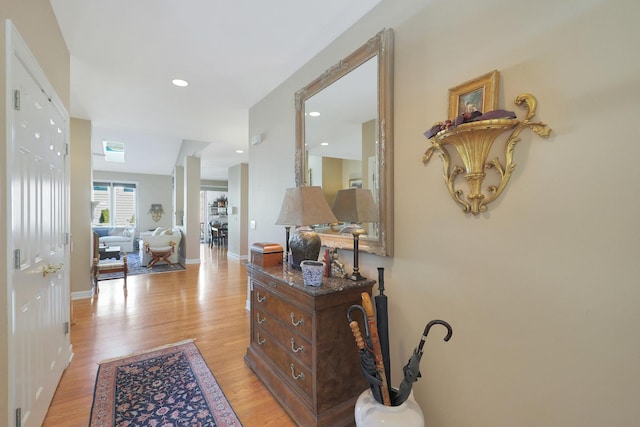 hall featuring baseboards, light wood finished floors, and recessed lighting