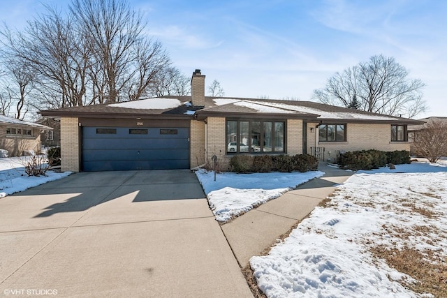 view of front of property featuring a garage, driveway, brick siding, and a chimney