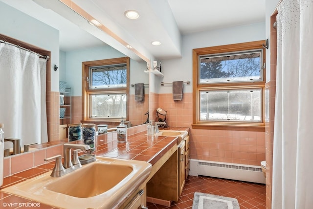 kitchen featuring tile counters, dark tile patterned flooring, a baseboard radiator, a sink, and tile walls