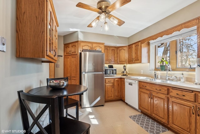 kitchen featuring appliances with stainless steel finishes, brown cabinets, light countertops, and a sink