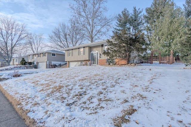 view of front of house featuring a garage, brick siding, and board and batten siding