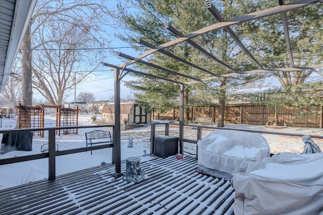 snow covered patio featuring an outdoor structure, fence, a grill, a pergola, and a storage unit