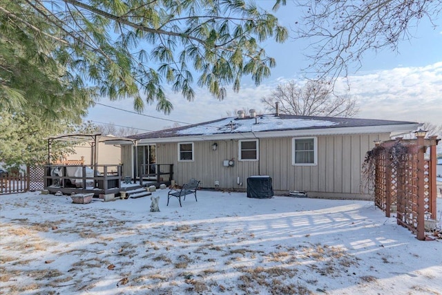 snow covered house featuring fence and a deck