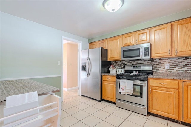 kitchen featuring appliances with stainless steel finishes, light tile patterned flooring, light stone counters, and decorative backsplash