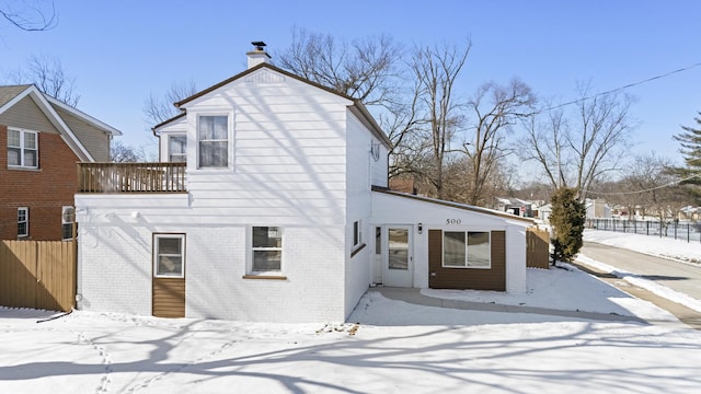 exterior space with a balcony, a chimney, fence, and brick siding