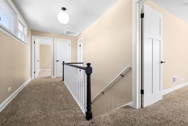 hall featuring baseboards, carpet floors, an upstairs landing, and attic access