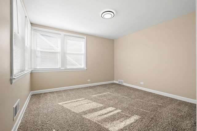 carpeted spare room with a healthy amount of sunlight, visible vents, and baseboards