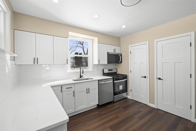 kitchen featuring stainless steel appliances, dark wood-type flooring, a sink, white cabinetry, and light countertops