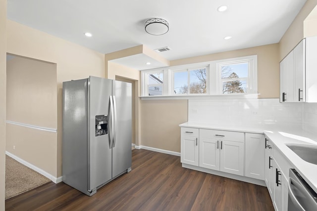 kitchen with light countertops, decorative backsplash, appliances with stainless steel finishes, dark wood-type flooring, and white cabinets