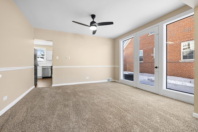 carpeted spare room with visible vents, a ceiling fan, and baseboards