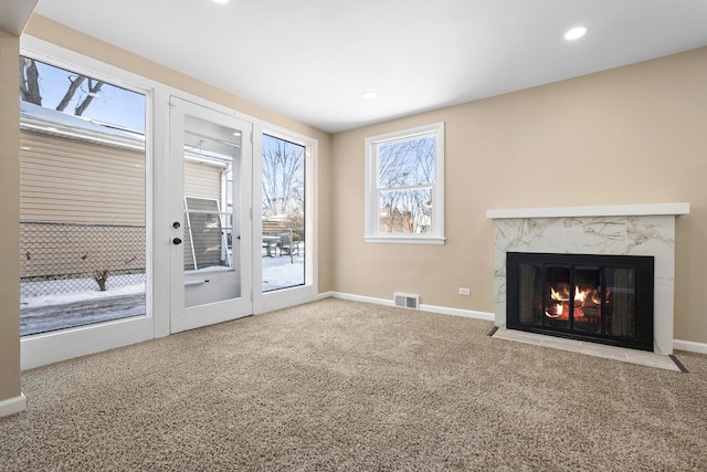 unfurnished living room with recessed lighting, visible vents, a premium fireplace, carpet flooring, and baseboards