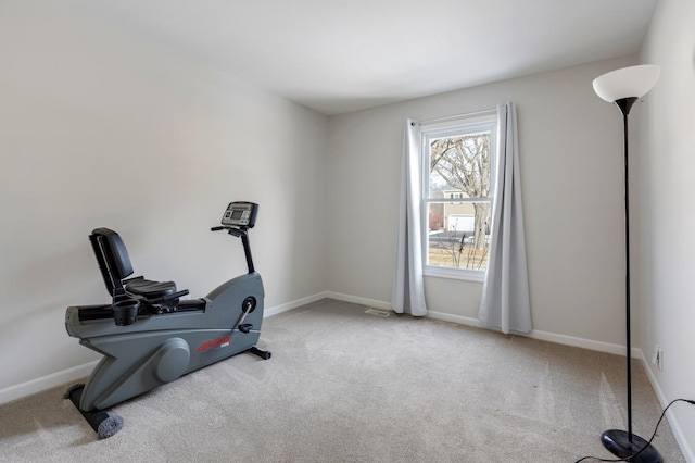 exercise area featuring light carpet and baseboards