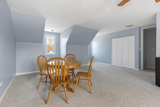 dining area with lofted ceiling, visible vents, baseboards, and light colored carpet