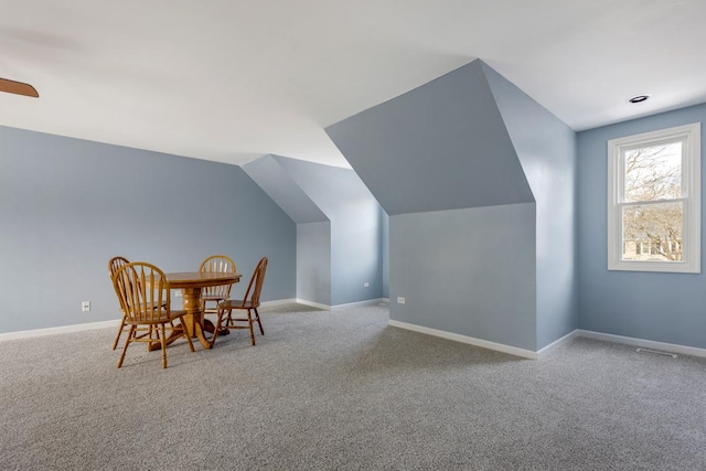 dining area with light carpet, vaulted ceiling, and baseboards