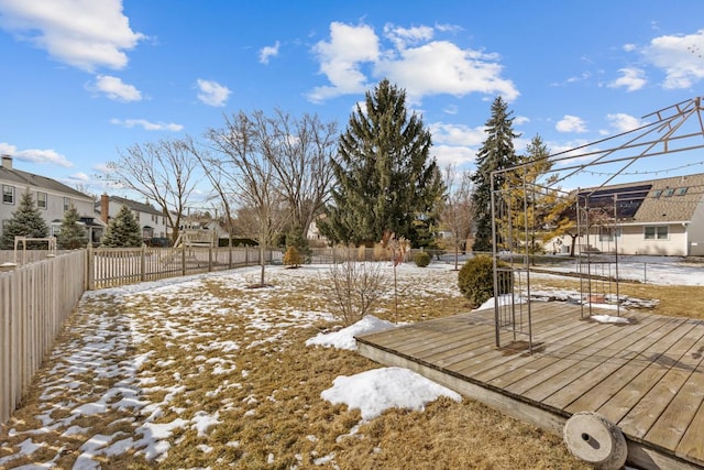 yard covered in snow featuring a residential view, fence, and a deck