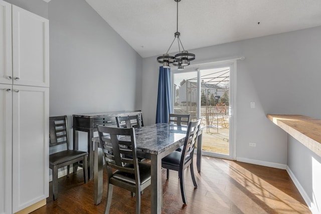 dining area with baseboards, a textured ceiling, wood finished floors, and an inviting chandelier