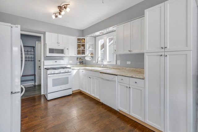 kitchen featuring light countertops, glass insert cabinets, white cabinets, a sink, and white appliances