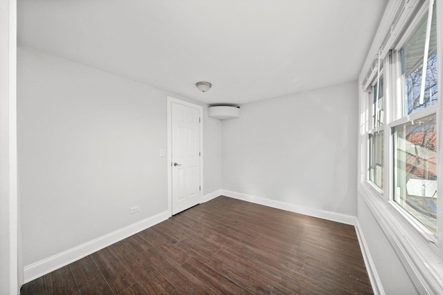 spare room with dark wood finished floors and baseboards