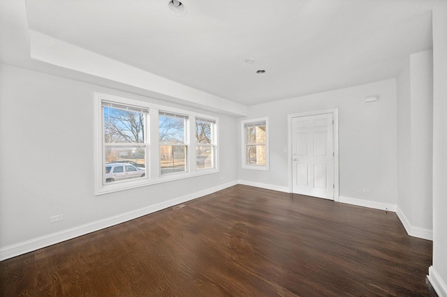 spare room featuring baseboards and dark wood finished floors