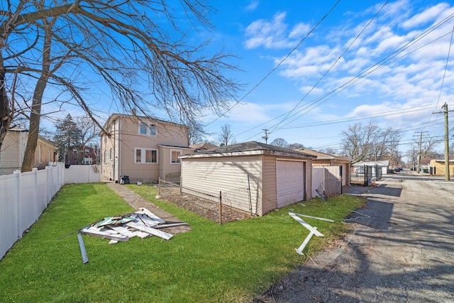 exterior space with a garage, driveway, an outbuilding, fence, and a yard