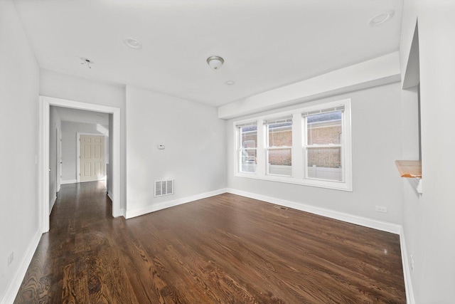 unfurnished room featuring visible vents, baseboards, and wood finished floors