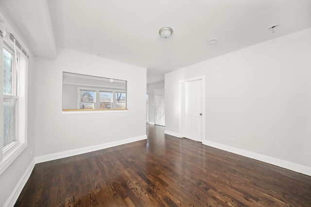 spare room with baseboards and wood finished floors