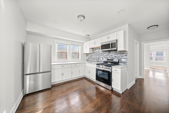 kitchen featuring stainless steel appliances, light countertops, dark wood finished floors, and tasteful backsplash