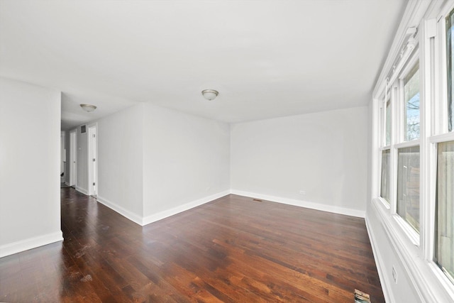 empty room with visible vents, baseboards, and dark wood finished floors