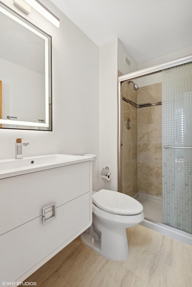 bathroom with a shower stall, toilet, and vanity