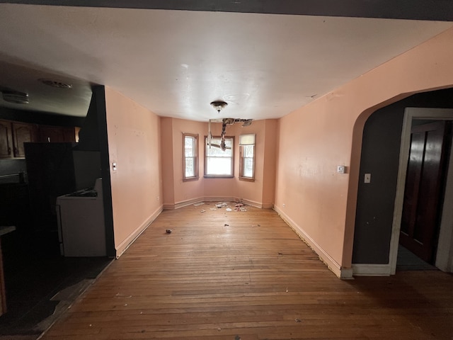 dining area with baseboards, arched walkways, washer / clothes dryer, and hardwood / wood-style floors