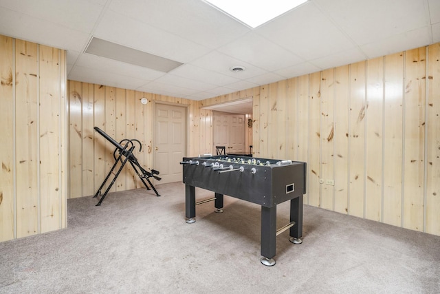 game room featuring a paneled ceiling, carpet flooring, and wood walls