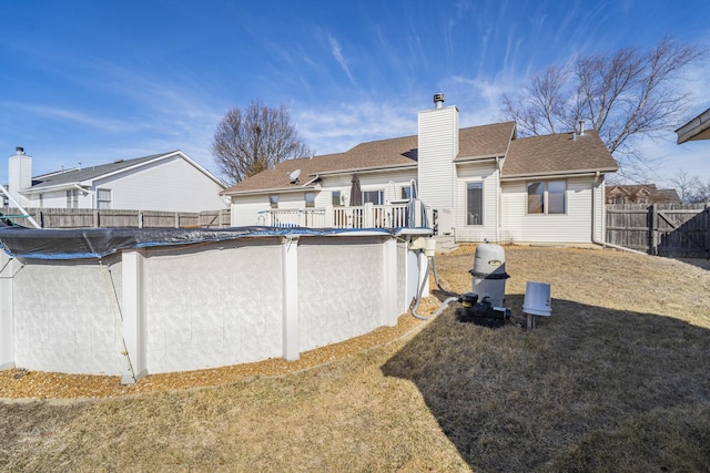 back of house featuring a fenced in pool, a fenced backyard, a lawn, and a chimney