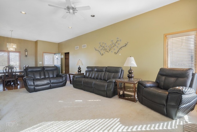 carpeted living room featuring visible vents and ceiling fan with notable chandelier