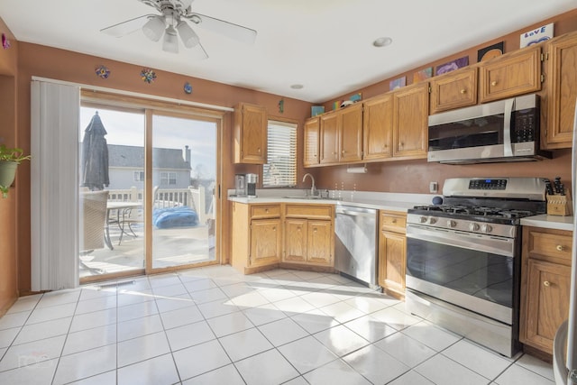 kitchen with light tile patterned floors, light countertops, appliances with stainless steel finishes, and a sink