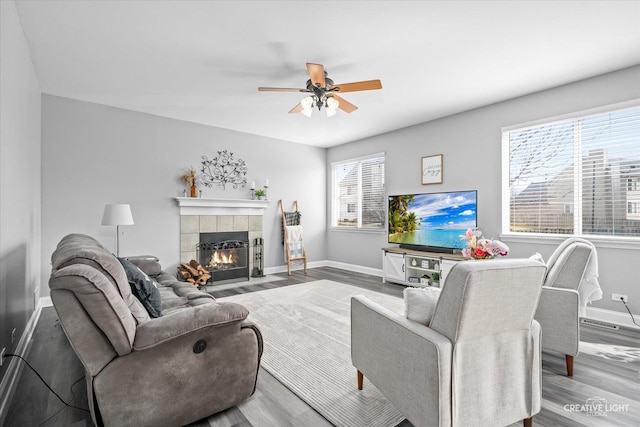 living room with a fireplace, wood finished floors, a ceiling fan, and baseboards