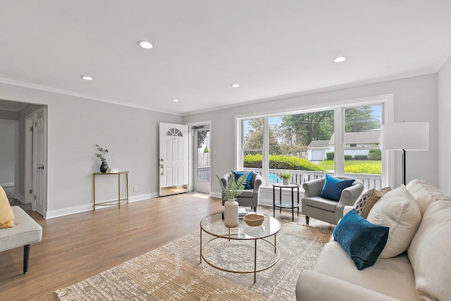 living room featuring light wood finished floors, baseboards, crown molding, and recessed lighting