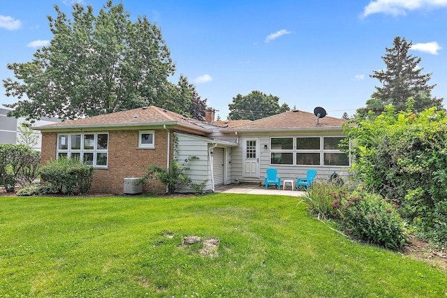 back of property featuring a yard, a chimney, brick siding, and a patio