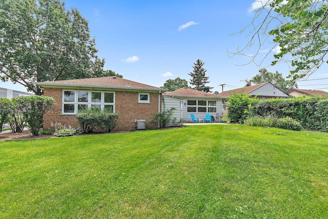 rear view of property with brick siding and a lawn