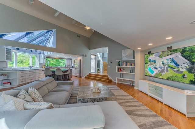 living area featuring recessed lighting, visible vents, stairway, high vaulted ceiling, and light wood-type flooring