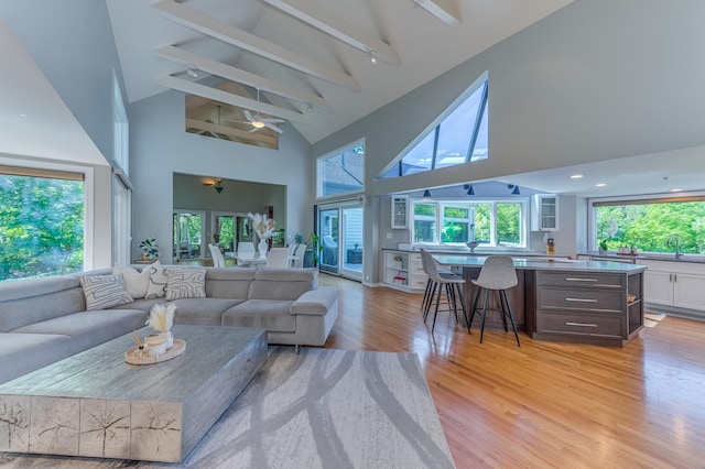 living room featuring high vaulted ceiling, beam ceiling, ceiling fan, and light wood finished floors