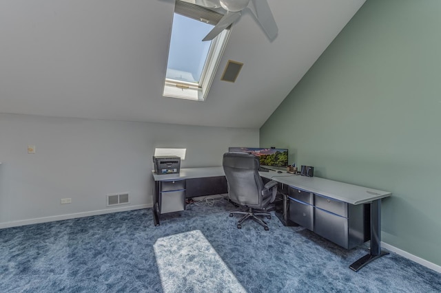 office featuring vaulted ceiling with skylight, visible vents, baseboards, ceiling fan, and dark carpet