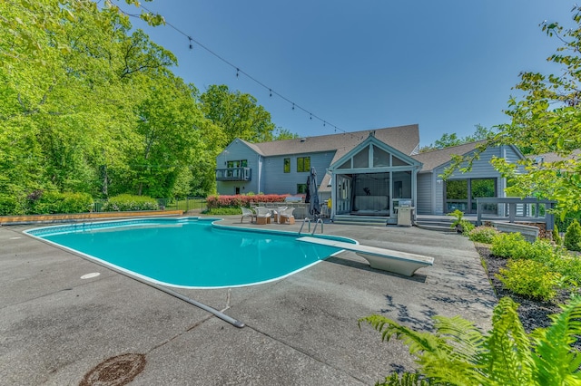 outdoor pool with a diving board and a patio area