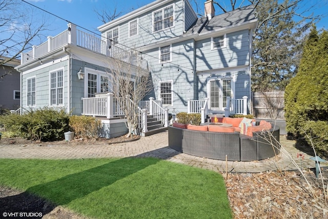 back of house featuring a balcony, a patio area, and a chimney