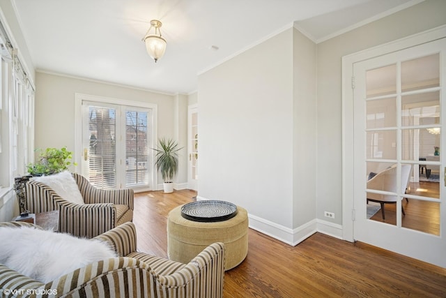 sitting room featuring baseboards, wood finished floors, and crown molding