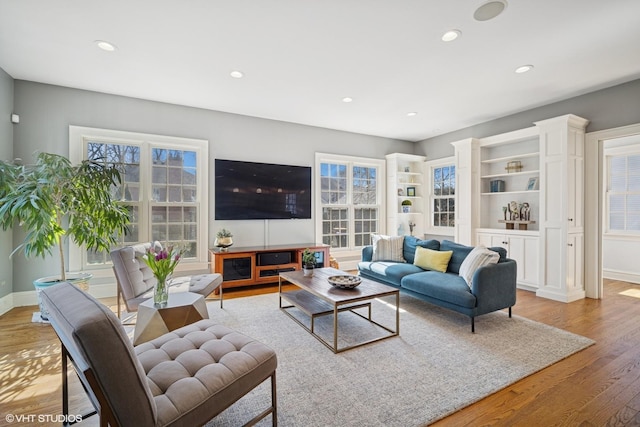 living area with a wealth of natural light, light wood-style flooring, and baseboards