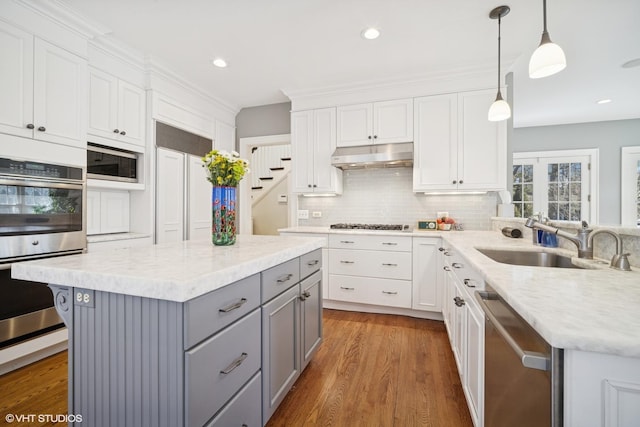 kitchen with stainless steel appliances, gray cabinets, white cabinetry, a sink, and under cabinet range hood