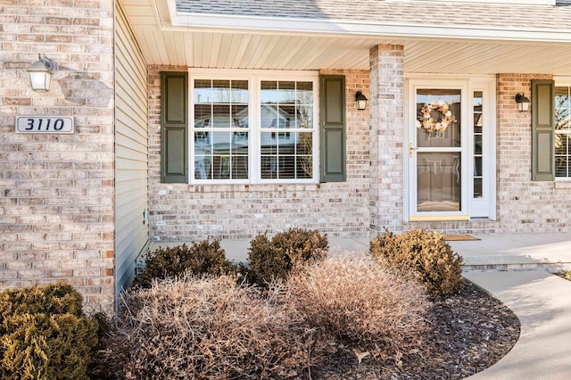 entrance to property with brick siding and roof with shingles