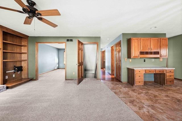 kitchen featuring carpet, built in desk, open shelves, light countertops, and visible vents